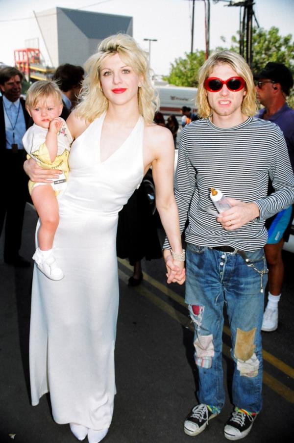 Courtney Love holding Frances Cobain on her hip and holding Kurt Cobain's hand 