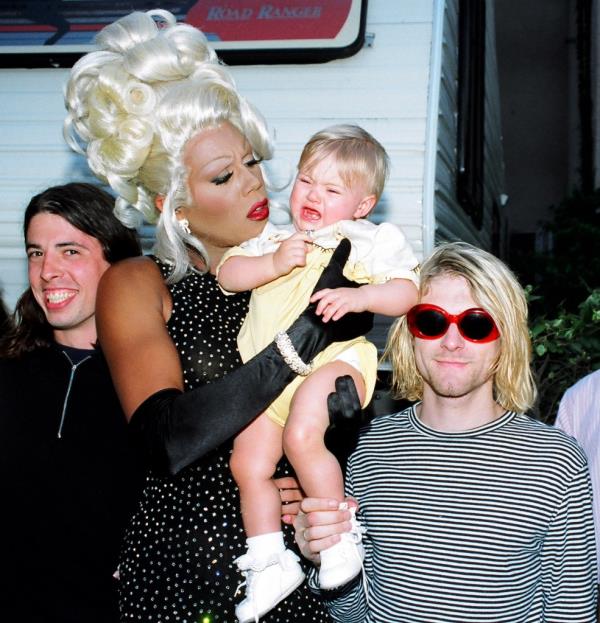 Baby Francs Cobain held by RuPaul, standing between Dave Grohl and Kurt Cobain