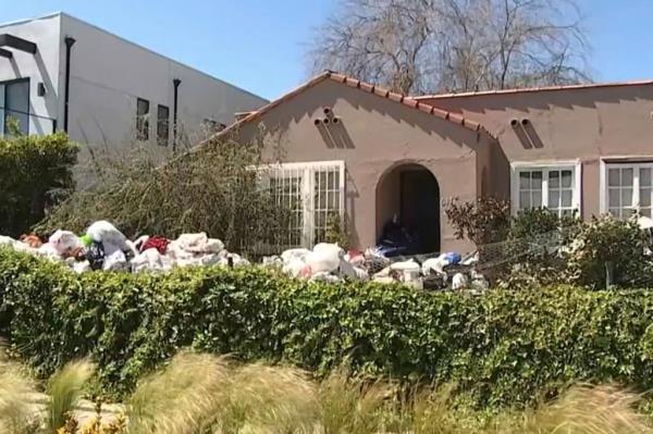 Picture of the outside of a home buried under mountains of trash.