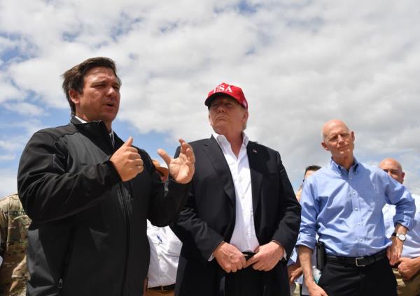 US President Do<em></em>nald Trump and Florida Republican US Senator Rick Scott (R) listen to Florida Governor Ron DeSantis (L) during a tour of the Edgar Hoover Dike on Lake Okeechobee in Florida, on March 29, 2019.