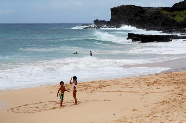 Two children playing on Sandy Beach in Honolulu, Hawaii in preparation for the arrival of Hurricane Douglas