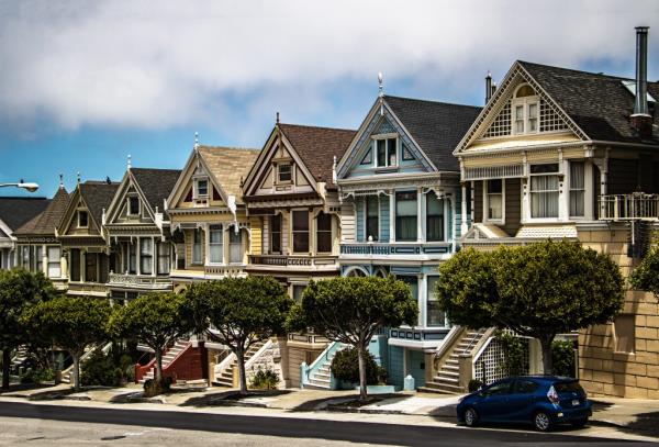 A row of colorful Victorian and Edwardian houses, known as Painted Ladies, lined up on a street with trees
