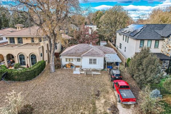 The tiny home sits between two much larger estates in a developed neighborhood. 