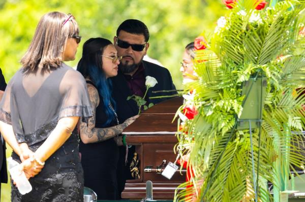 Alexis Nungaray placing a white rose on her daughter's casket.