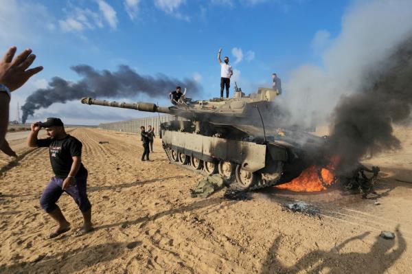 Palestinians celebrate by a destroyed Israeli tank at the Gaza Strip fence east of Khan Younis southern on Saturday.