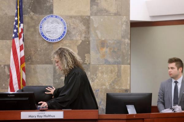 Clark County District Judge Mary Kay Holthus standing in court for a hearing, with her marshal and law clerk by her side.