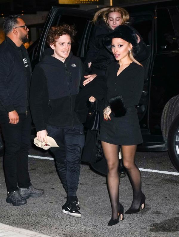Ariana Grande walking with Ethan Slater, smiling. 