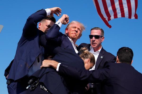 Bleeding Do<em></em>nald Trump is surrounded by U.S. Secret Service agents after an assassination attempt at a campaign rally, Saturday, July 13, 2024, in Butler, Pa.