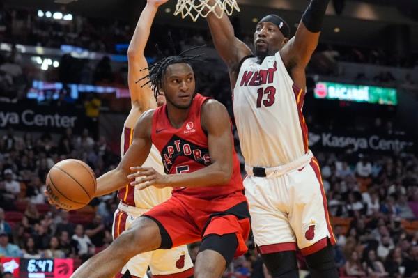 Raptors guard Immanuel Quickley (5) looks to pass under pressure from Miami Heat center Bam Adebayo (13) during the second half of an NBA basketball game.