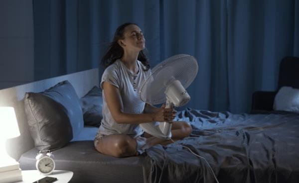 Woman enjoying fresh air in front of a fan