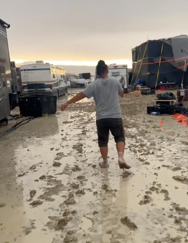 Burning Man participant walking barefoot through mud
