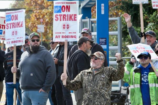 Unio<em></em>n machinists wave signs next to company's factory in Everett, Wash., on Tuesday, Oct. 22, 2024. 