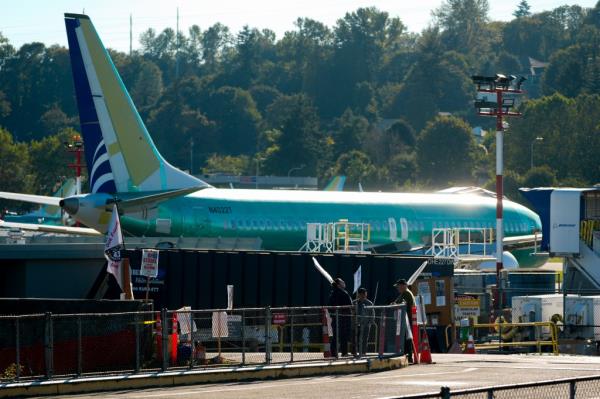 Boeing employees hold picket signs while striking in front of unpainted Boeing 737 Max aircraft Tuesday, Sept. 24, 2024, next to the company's facilities in Renton, Wash.