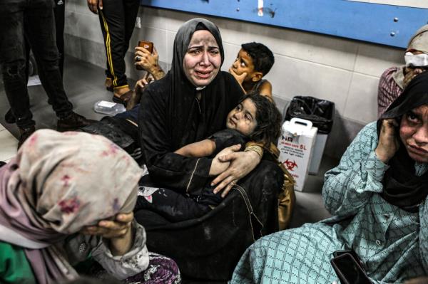 Palestinians wounded at Ahli Arab hospital sit on the floor at al-Shifa hospital, in Gaza City, central Gaza Strip, Tuesday, Oct. 17, 2023. 