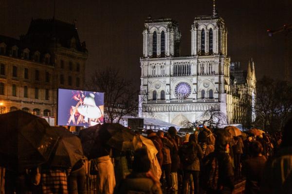 People watch the reopening ceremony of the Notre-Dame Cathedral in a giant screen on the banks of the River Seine. Notre-Dame Cathedral in Paris has reopened its doors after five and a half years of restoration due to the 2019 fire.