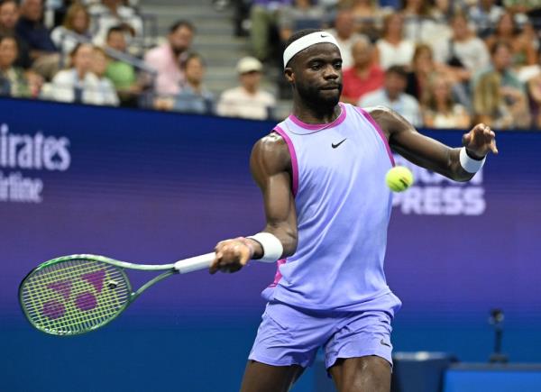 Frances Tiafoe swinging a tennis racket at the US Open on Arthur Ashe Stadium, advancing to the quarterfinals
