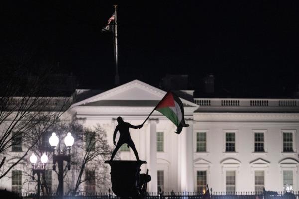A protestor waves a Palestinian flag with the White House in the background during the 