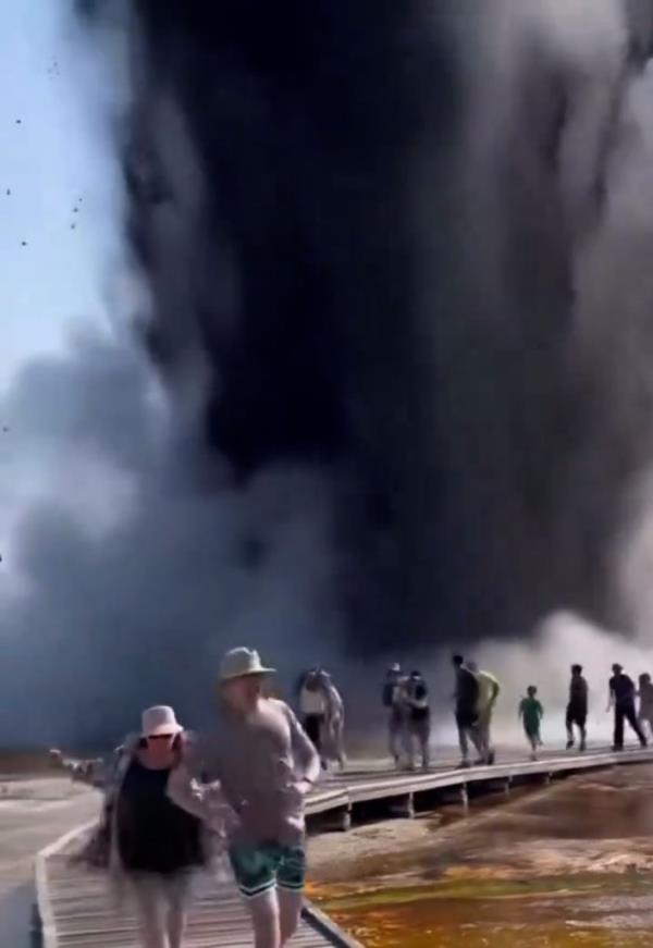 Group of tourists running away from the explosion on a boardwalk.