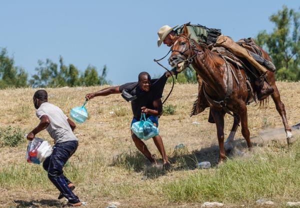 Border Patrol agent on horseback tries to stop a Haitian migrants from entering an encampment on the banks of the Rio Grande river
