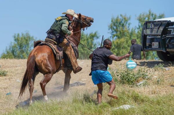 A horseback Border Patrol agent and a Haitian migrant 
