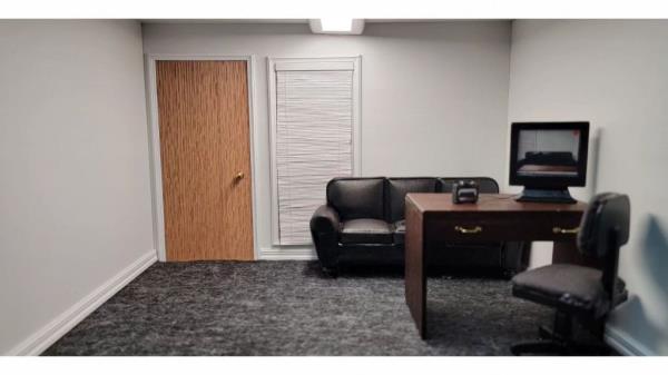 A couch, camera co<em></em>nnected to omputer monitor, camera, grey carpeting, a table, and camer