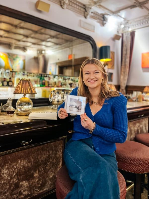 Lucy White sits at the Lobby Bar in the Chelsea Hotel holding a Taylor Swift album. 