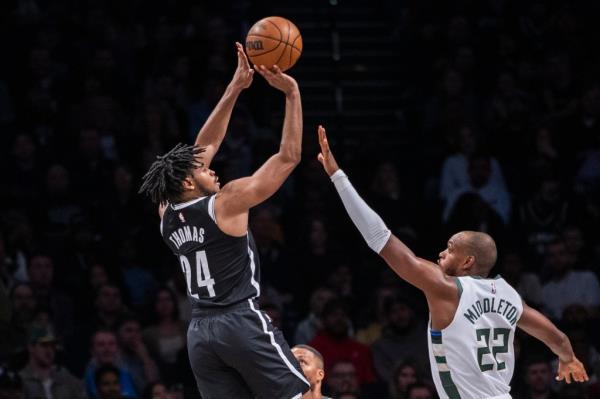 Nets guard Cam Thomas (24) shots over Milwaukee Bucks forward Khris Middleton (22)
