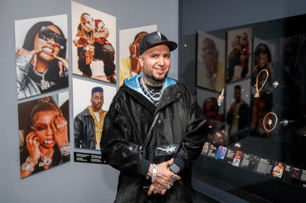 David Tamargo, also known as Alligator Jesus, standing in front of a wall with pictures at the Ice Cold: An Exhibition of Hip-Hop Jewelry event at the American Museum of Natural History