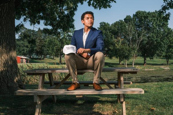 Elias Cunningham sitting on a picnic table, holding a 