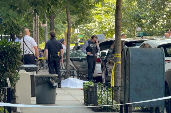 Police officers on the sidewalk at the scene of a shooting on East 88th Street, Upper East Side, Manhattan