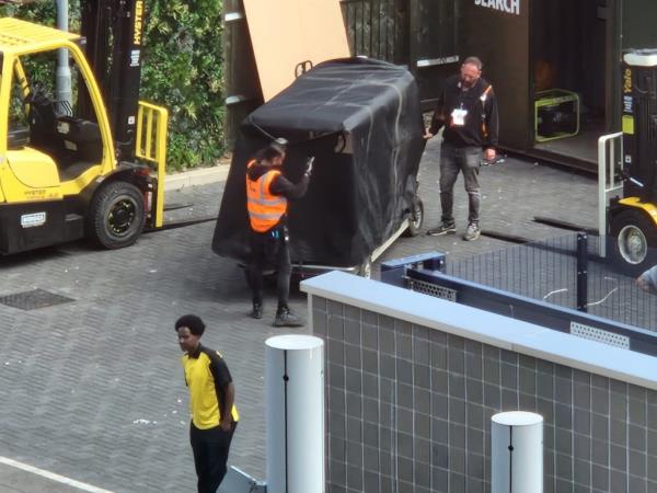 A golf cart shrouded in black with roadies. 