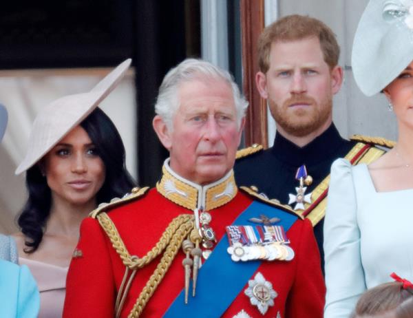 Meghan, Duchess of Sussex, Prince Charles, Prince of Wales and Prince Harry, Duke of Sussex standing on the balcony of Buckingham Palace during Trooping The Colour 2018 ceremony with guardsmen and cavalry in the foreground.