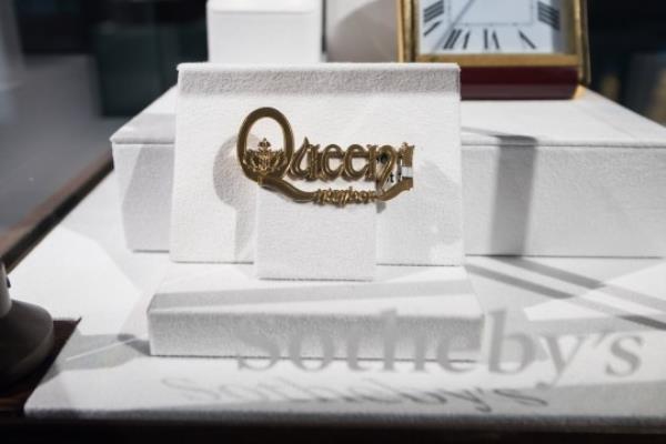 LONDON, UNITED KINGDOM - AUGUST 03: A gold Cartier brooch with the words 'Queen Number 1' (estimate 4,000-6,000) is displayed during a photocall at Sotheby's auction house for the unveiling of Freddie Mercury's entire private collection ahead of an exhibition and six dedicated sales in London, United Kingdom on August 03, 2023. 'Freddie Mercury: A World of His Own' exhibition starring stage costumes, handwritten lyrics, fine and decorative arts, Japanese art, precious objects and a trove of perso<em></em>nal belo<em></em>ngings will be open to the public between August 4th and September 5th, before the items are offered across six dedicated auctions, each one devoted to a different aspect of Mercurys life, both public and private. (Photo by Wiktor Szymanowicz/Anadolu Agency via Getty Images)