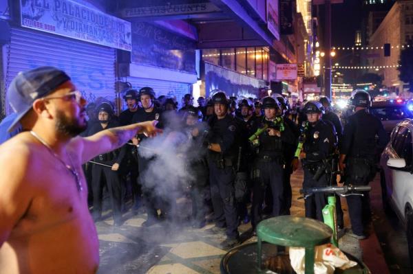 A police officer shoots a foam bullet at a Dodgers fan on the street during celebrations