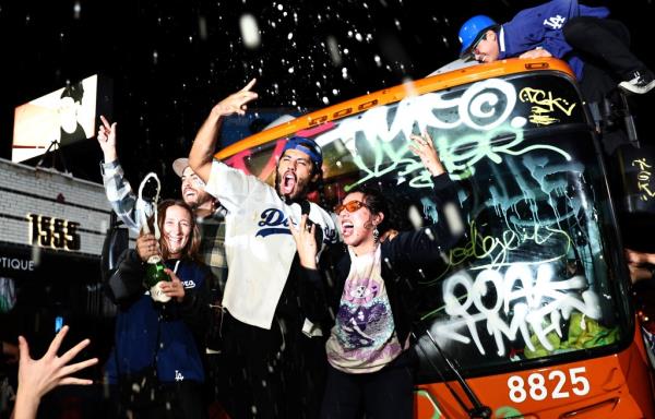celebrate in Echo Park in front of a bus that was tagged after the Los Angeles Dodgers defeated the New York Yankees in Game 5