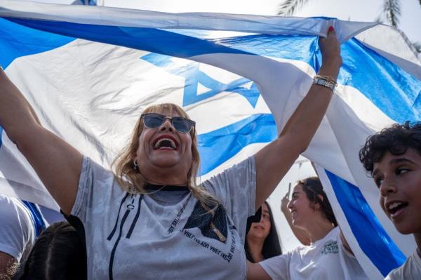 A woman joyfully wrapped in an Israeli flag celebrating on the streets after the safe return of four Israeli hostages