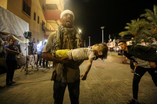 A man carries the body of a Palestinian girl who was killed during Israeli raids.