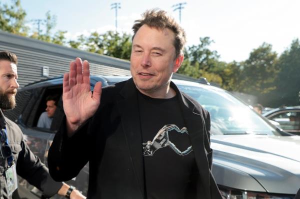 Elon Musk attending the Men's Final of the 2024 US Open Tennis Champio<em></em>nships in New York City, waving in sunlight.