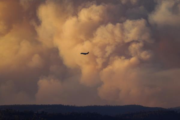 An air tanker fighting the Park Fire near Chico, California, flies through billowing smoke clouds.