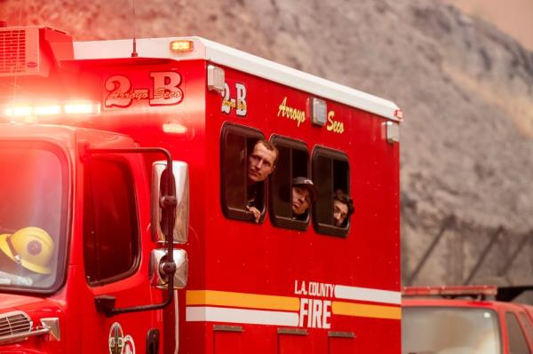 Three firefighters poke their heads out of the window of an LA Fire truck to catch a glimpse of the Park Fire  in Tehama County, California.