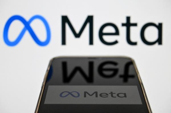 me<em></em>ta logo on smartphone screen and me<em></em>ta logo in background on wall.