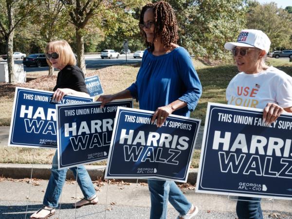 Supporters carrying placards for Kamala Harris and Tim Walz on the roadside in Suwanee, Georgia