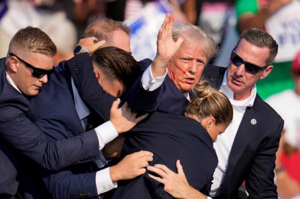 Trump is helped off the stage by Secret Service agents after being targeted in the assassination attempt at a campaign rally in Butler, Pa., on Saturday, July 13, 2024.