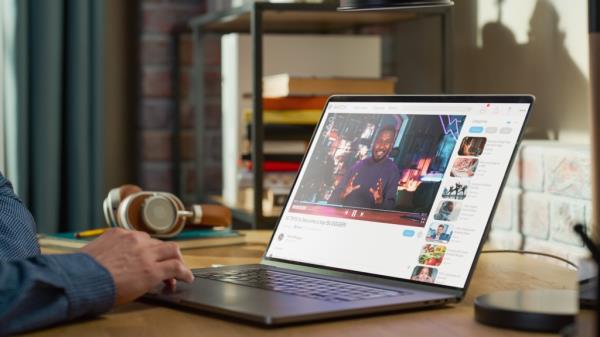 Man watching YouTube in a home office on a laptop