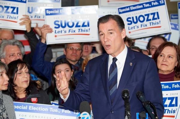 Tom Suozzi speaking into micropho<em></em>nes at campaign HQ during a rally with volunteers.