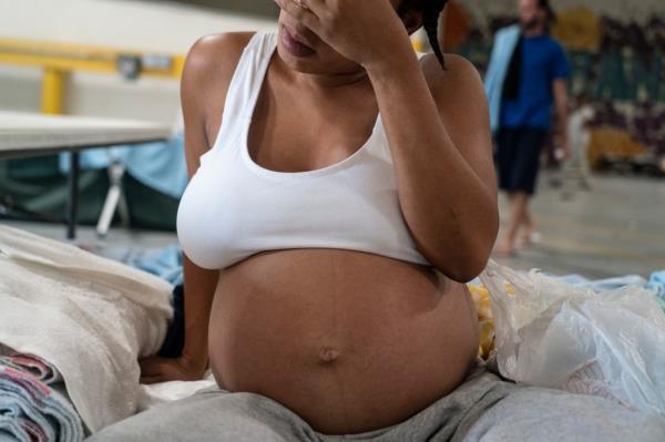 A pregnant migrant with her belly exposed rests at Annunciation House in El Paso.
