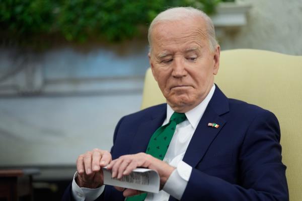 Biden folds the cheat cards while looking down.