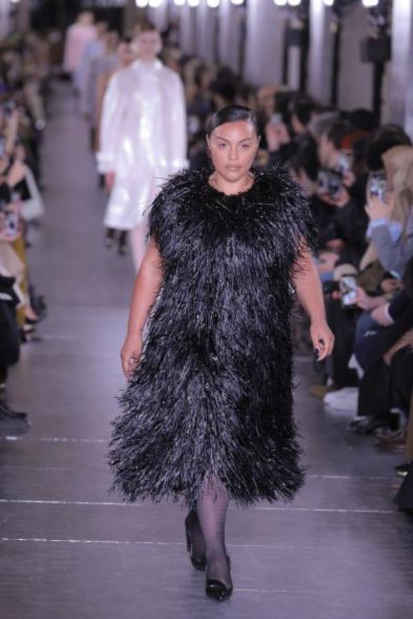 Paloma Elsesser walks the runway during a fashion show wearing a black dress.