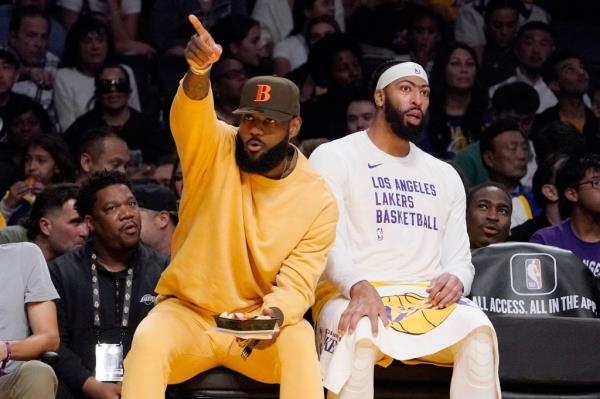 Los Angeles Lakers forward LeBron James gesturing to fans whilst sitting on bench with forward Anthony Davis during a basketball game