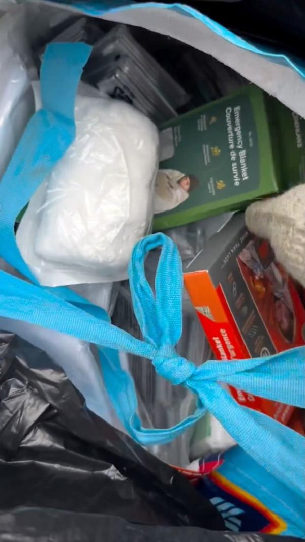 Boxes of emergency blankets stuffed in plastic bags in a garbage pile